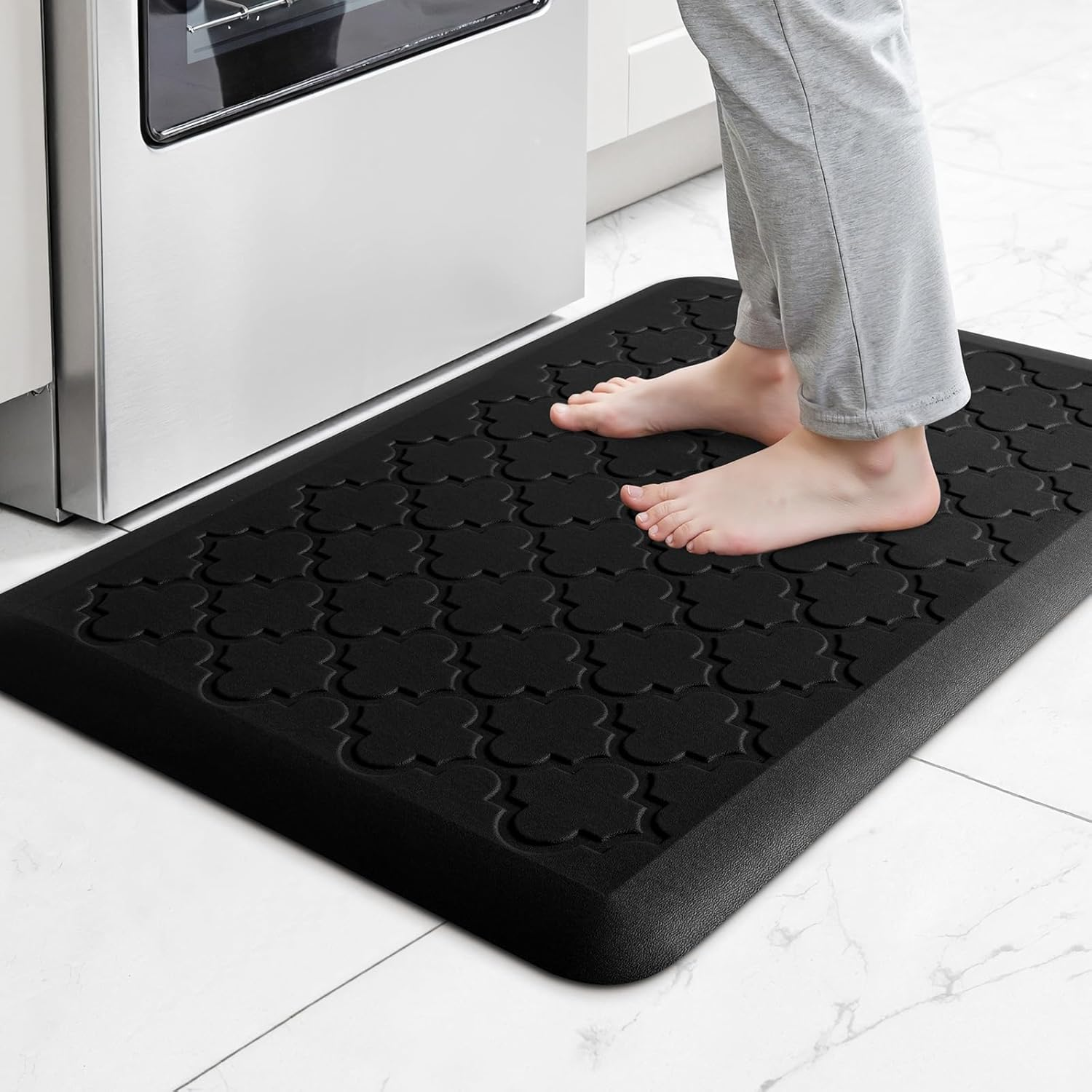 Person standing barefoot on a black cushioned anti-fatigue kitchen mat with bevelled edges