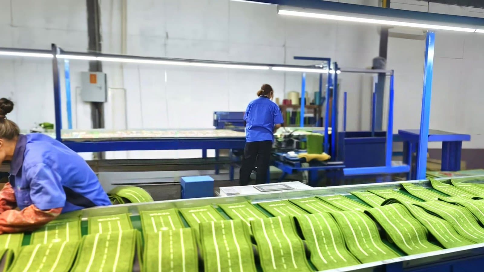 Workers inspecting and trimming mats on a production line before packing