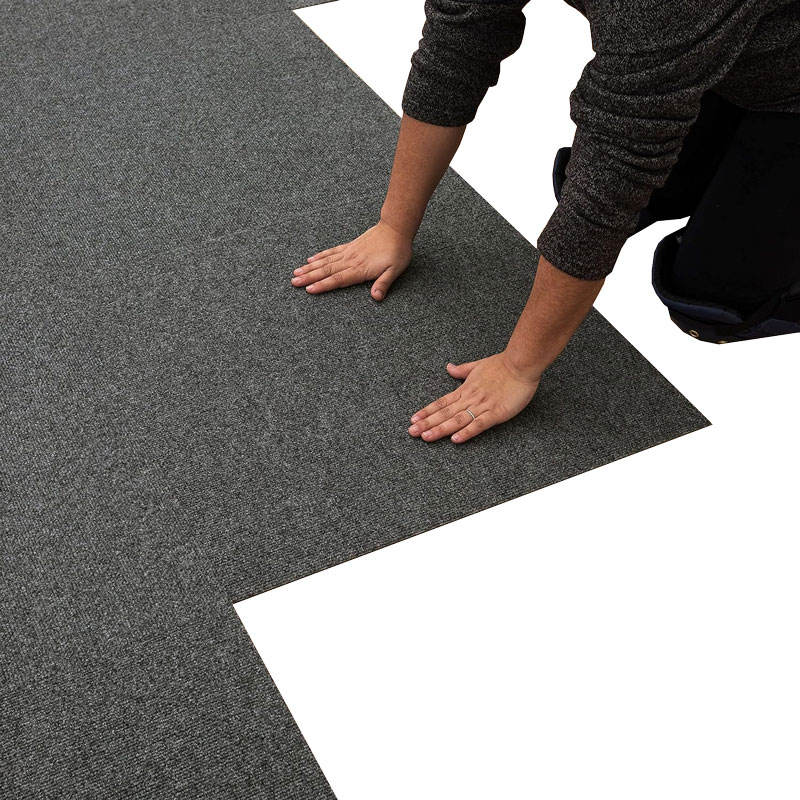 Installer fitting modular carpet tiles on an office floor