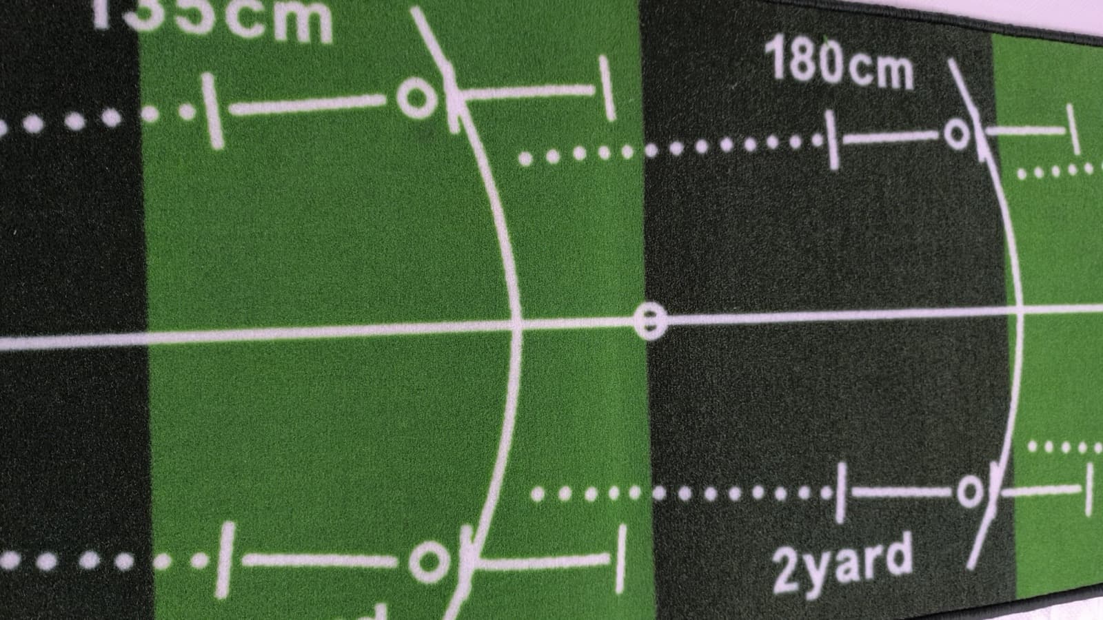 Close-up of the printed distance markings on a golf putting mat